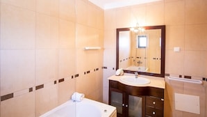 A modern bathroom with a bathtub, a sink, and a large mirror. - Jardins de Pera (Silves)