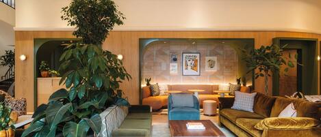 A modern living room with a sofa set, coffee table, and large potted plants.