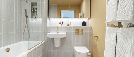 A modern bathroom with a glass-enclosed shower, a white sink, and a toilet.