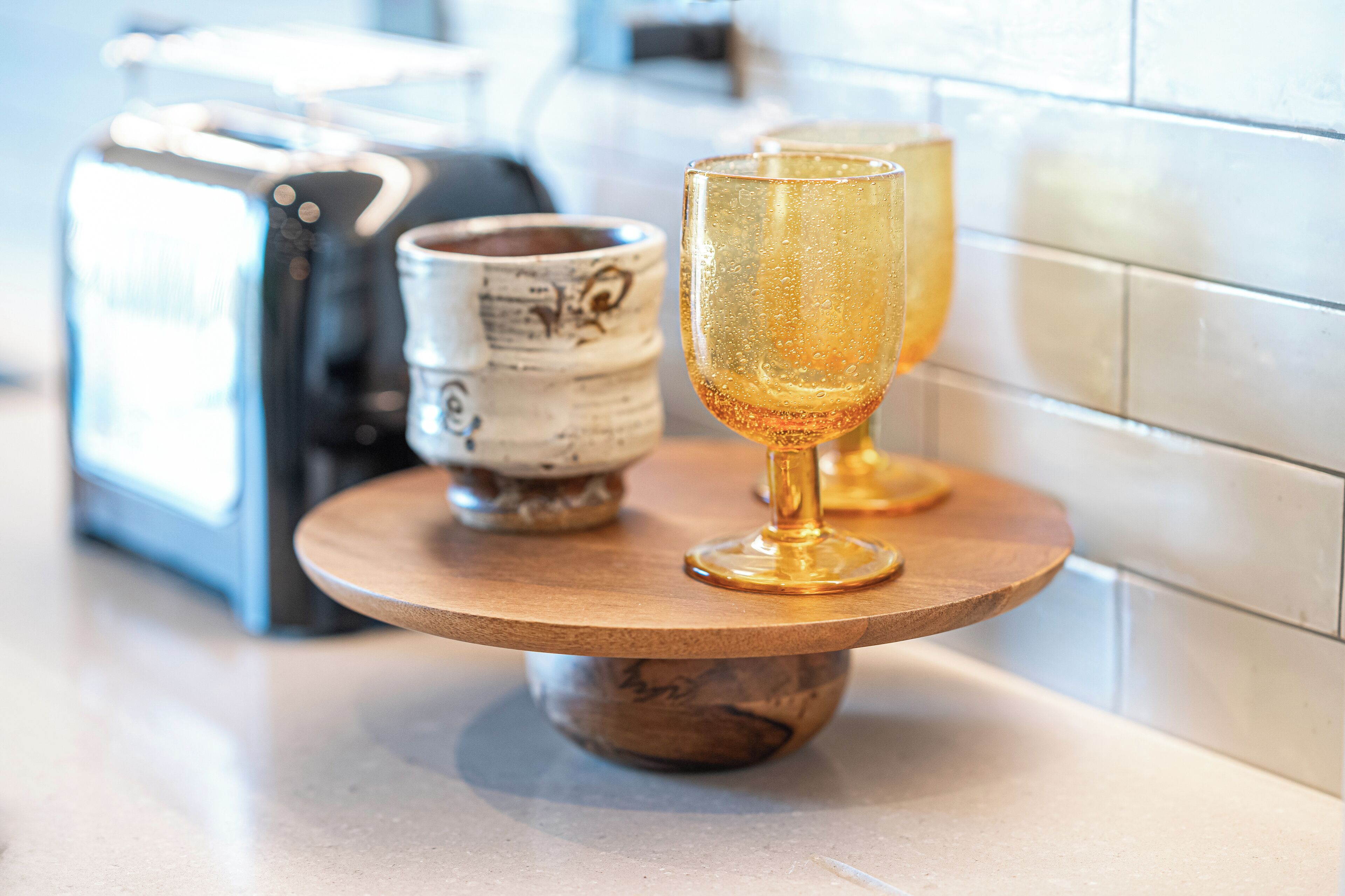 Ein runder Holztisch mit einem Glas und einer Keramiktasse darauf.