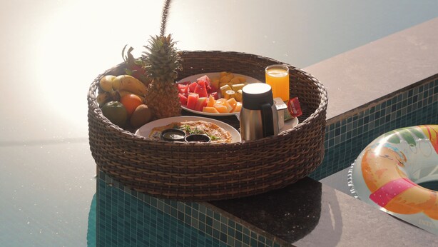 A wicker basket filled with fruits and a thermos on a poolside. - Nazaara Hills Retreat (Udaipur)