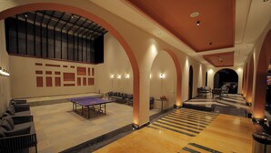 A spacious lobby with a ping pong table, seating areas, and a staircase. - Nazaara Hills Retreat (Udaipur)