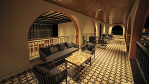 A spacious indoor area with a checkered floor, seating arrangements, and a wooden ceiling. - Nazaara Hills Retreat (Udaipur)