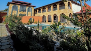 A building with a pool, arched windows, and a red roof. - Nazaara Hills Retreat (Udaipur)