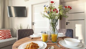 A breakfast setup with croissants, orange juice, and a vase of flowers. - SPV Apart Pileckiego 258 (Warszawa)