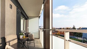 A balcony with two chairs and a table, a potted plant, and a glass of orange juice. - SPV Apart Pileckiego 258 (Warszawa)