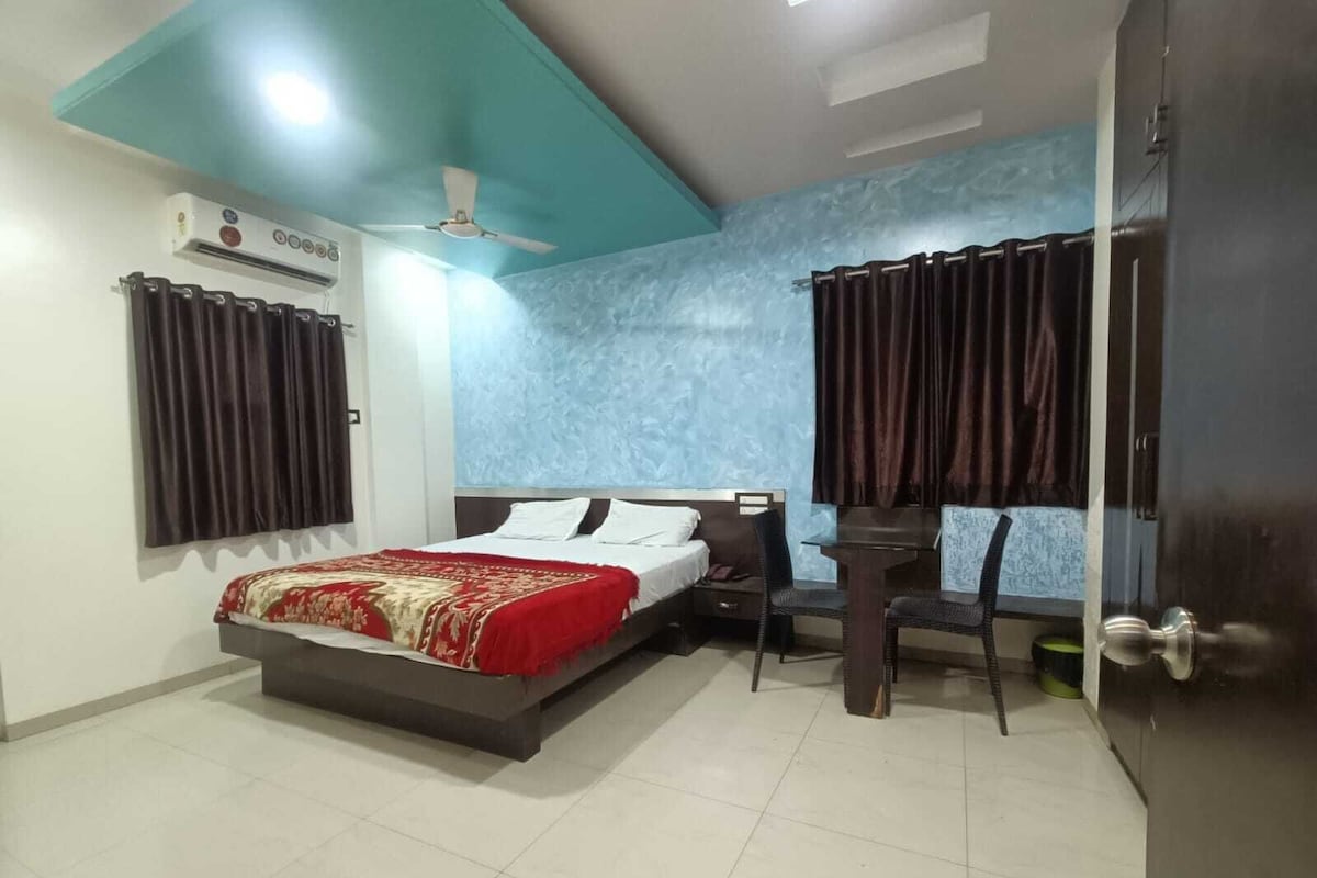 A bedroom with a bed, a desk, a chair, a ceiling fan, and an air conditioning unit.