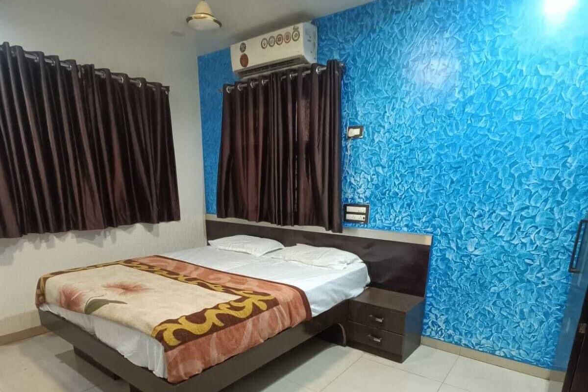 A bedroom with a bed, a nightstand, a wall-mounted air conditioner, and a ceiling fan.