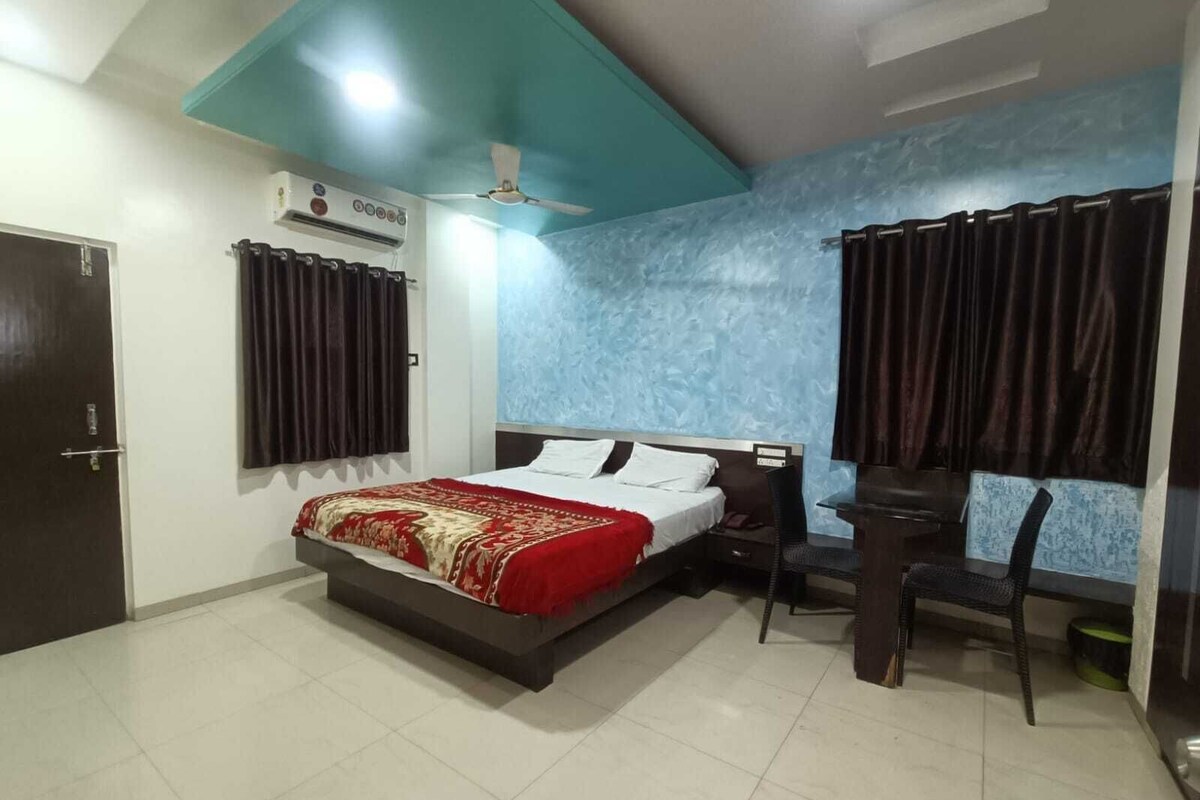A bedroom with a bed, a desk, a chair, a ceiling fan, and a window with curtains.