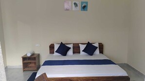 Ein ordentlich eingerichtetes Schlafzimmer mit Bett, Nachttisch, Stuhl und einem kleinen Holzschrank.