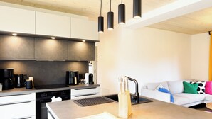 A modern kitchen with a large island, built-in appliances, and pendant lighting.