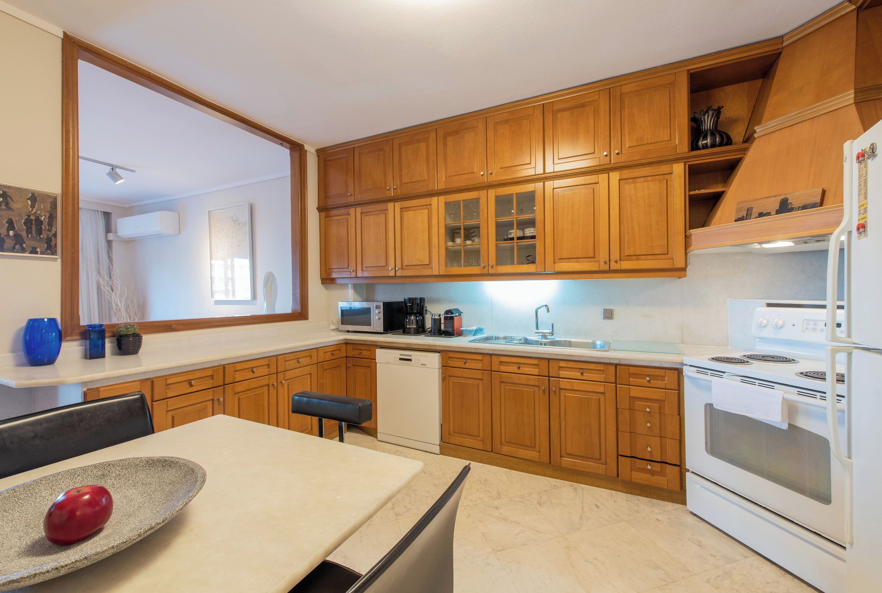 Cucina con mobili in legno, forno a microonde, lavastoviglie e piano cottura.