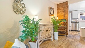 Une cuisine moderne avec des armoires blanches, un mur d’accent en bois et une horloge au mur.