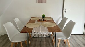 A dining table with four white chairs, a wooden floor, and a door in the background.