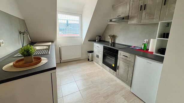 A modern kitchen with a built-in oven, a kettle, and a window with a view of a bridge.