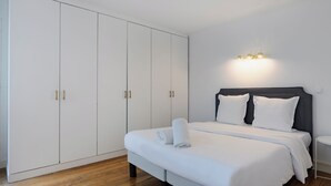A bedroom with a large wardrobe, a bed with white linens, and a bedside table. - Paris Center Rivoli residence (Paris)