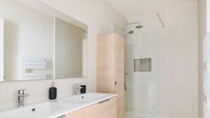 A modern bathroom with two sinks, a large mirror, a glass-enclosed shower, and a wooden cabinet. - Paris Center Rivoli residence (Paris)