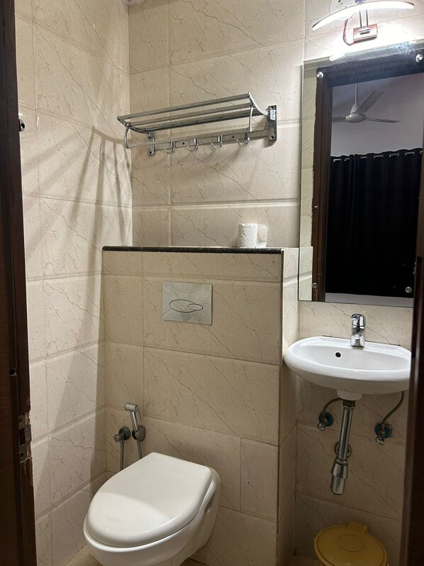 A bathroom with a toilet, sink, towel rack, and a mirror.
