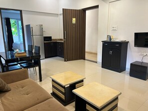 Una sala de estar moderna con un sofá, una mesa de comedor y una zona de cocina con refrigerador y microondas.