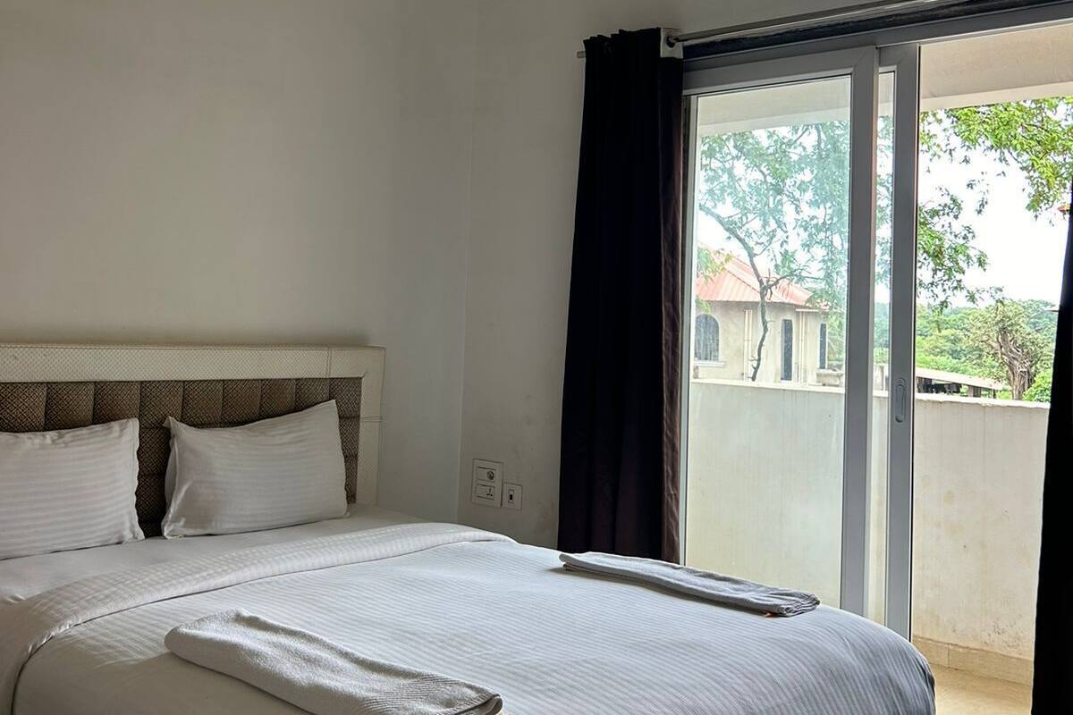 Un dormitorio con una cama, un ventilador de techo y vistas al exterior a través de una puerta corrediza de vidrio.