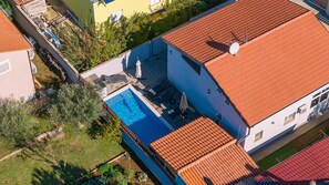 Luftaufnahme eines Wohnhauses mit Schwimmbad, rotem Ziegeldach und Garten.