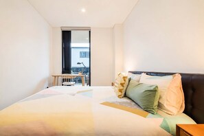 A bedroom with a bed, a desk, and a window. - Modern 2BR | Central Christchurch Stay (Christchurch)