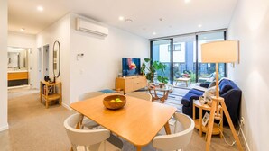 Ein modernes Wohnzimmer mit Essbereich, einer Couch, einem Fernseher und einem Balkon mit Blick.