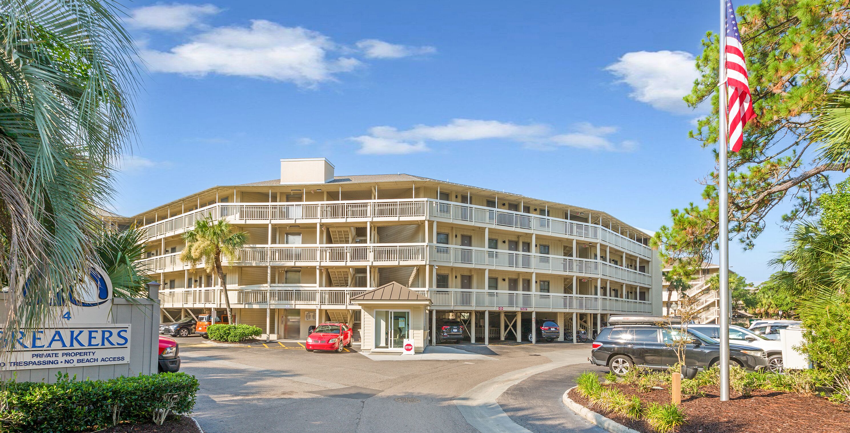 Un hôtel à plusieurs étages, doté d’une façade incurvée, d’un parking et d’un panneau indiquant qu’il s’agit d’une propriété privée sans accès à la plage.