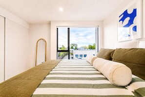 Ein Schlafzimmer mit einem Bett, Blick durch eine Glastür und einem Bild an der Wand.