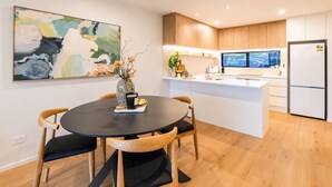 Una cocina moderna con una isla central, armarios de madera y un comedor con una mesa redonda y sillas.