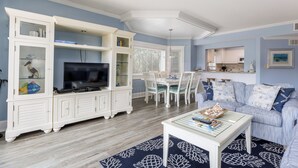 A living room with a TV, white cabinets, a dining table, and a sofa.