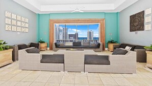 A spacious living room with a large window, a sofa set, and decorative wall art. - Coastal Comfort 1BRM at Towers of Chevron (Gold Coast)