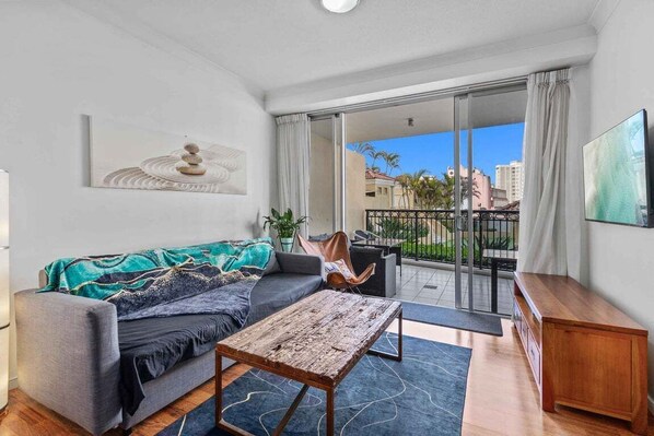 Ein modernes Wohnzimmer mit Sofa, Couchtisch und Blick auf den Außenbalkon.