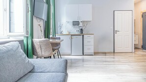 A modern kitchen with white cabinets, a built-in microwave, and a small refrigerator.