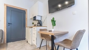 A compact kitchen with a microwave, coffee maker, and a potted plant.