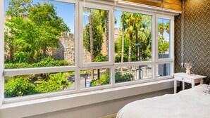 A bedroom with a large window, a bed, a small table, and a patterned wall. - Maxihomes Hadrian Nest (Antalya)