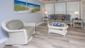 A living room with a wicker chair, a glass coffee table, a sofa, and a ceiling fan. - Renovated, 3 Bedroom Beach House - Sun Dog (Surfside Beach)