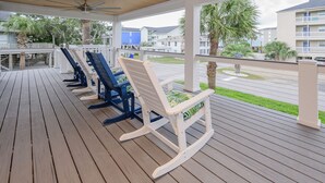 A covered outdoor area with wooden flooring and several rocking chairs. - Renovated, 3 Bedroom Beach House - Sun Dog (Surfside Beach)