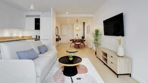 Un salon moderne avec un canapé, une table basse et un téléviseur fixé au mur.
