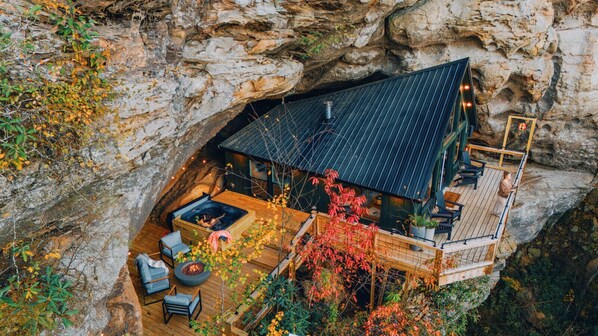 A cliffside cabin with a hot tub, outdoor seating, and a deck overlooking a rocky landscape. - NEW Cliffside Unique Stay | Hot Tub | Steam Shower (Beattyville)