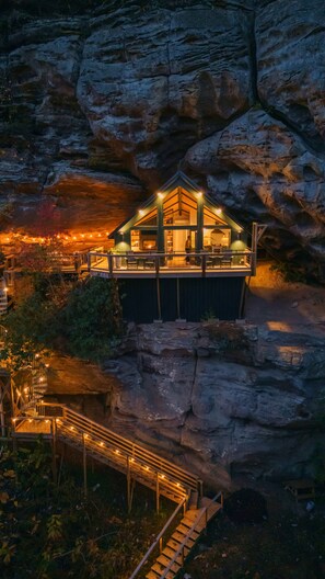 A mountain lodge with a wooden exterior and a balcony, surrounded by rocky terrain. - NEW Cliffside Unique Stay | Hot Tub | Steam Shower (Beattyville)