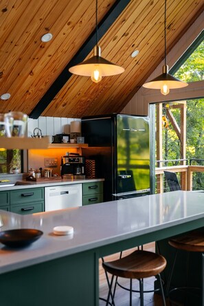 A modern kitchen with a large island, pendant lighting, and a view of the outdoors.