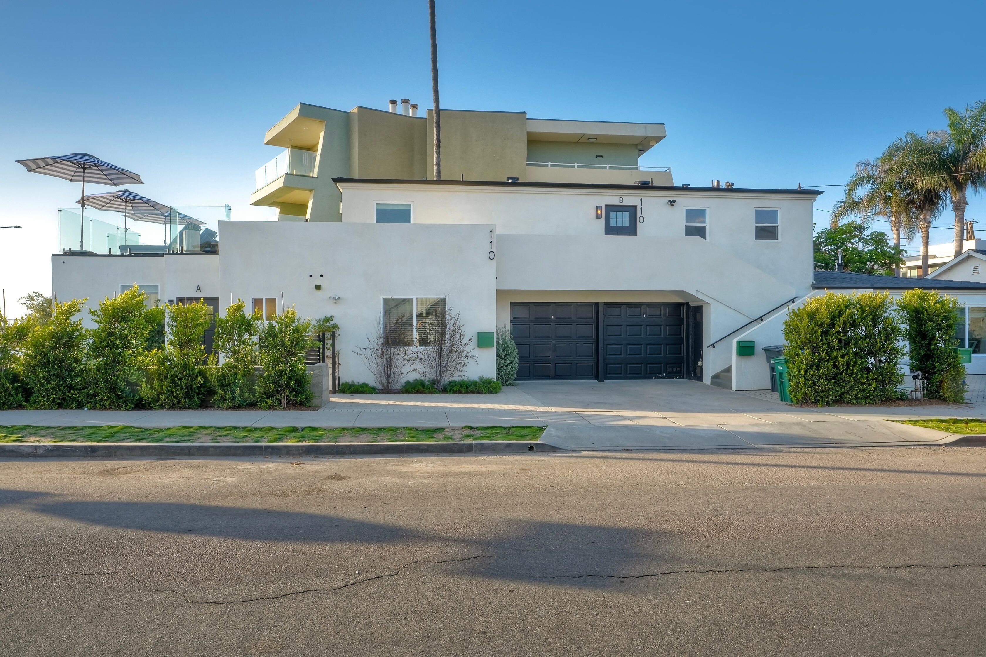 A modern two-story house with a garage, a balcony, and a well-maintained lawn.