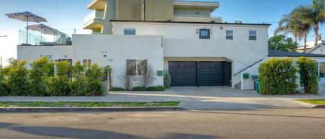 A modern two-story house with a garage, a balcony, and a well-maintained lawn.