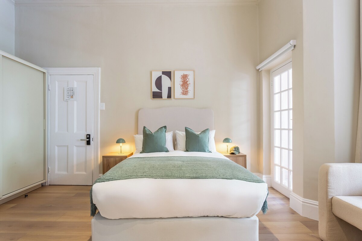 A bedroom with a bed, two bedside tables, a door, and a window.