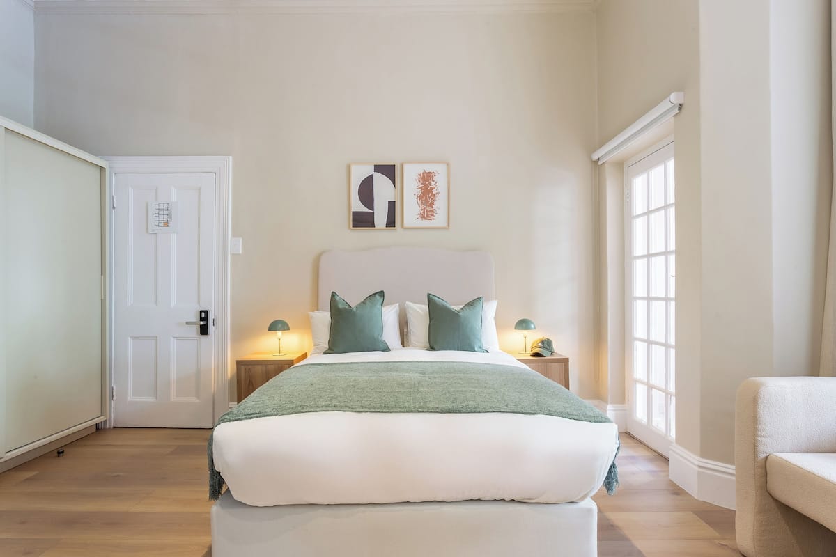 A bedroom with a bed, two bedside tables, a door, and a window.