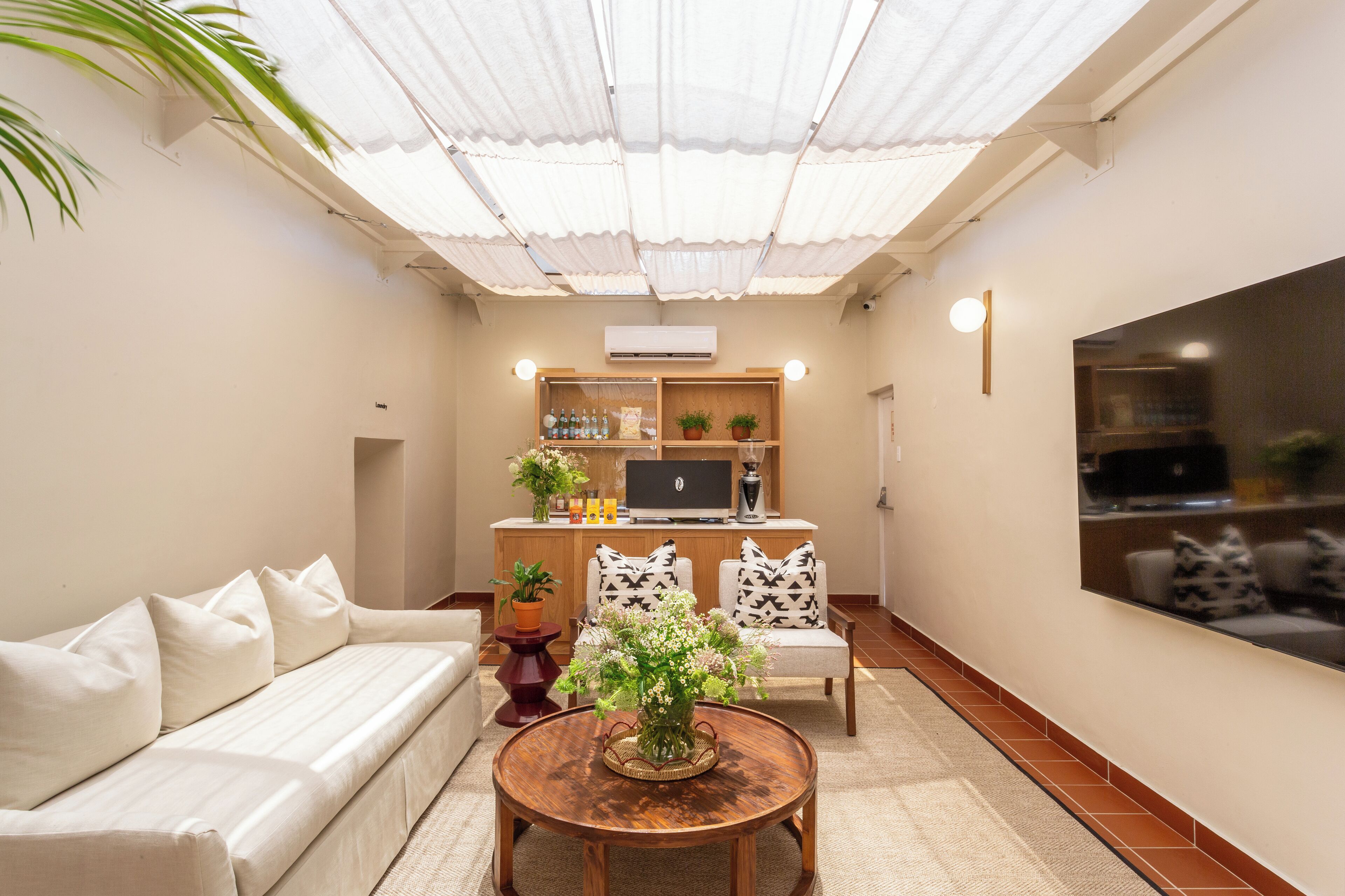A living room with a sofa, a round wooden coffee table, a TV, and a cabinet with plants.