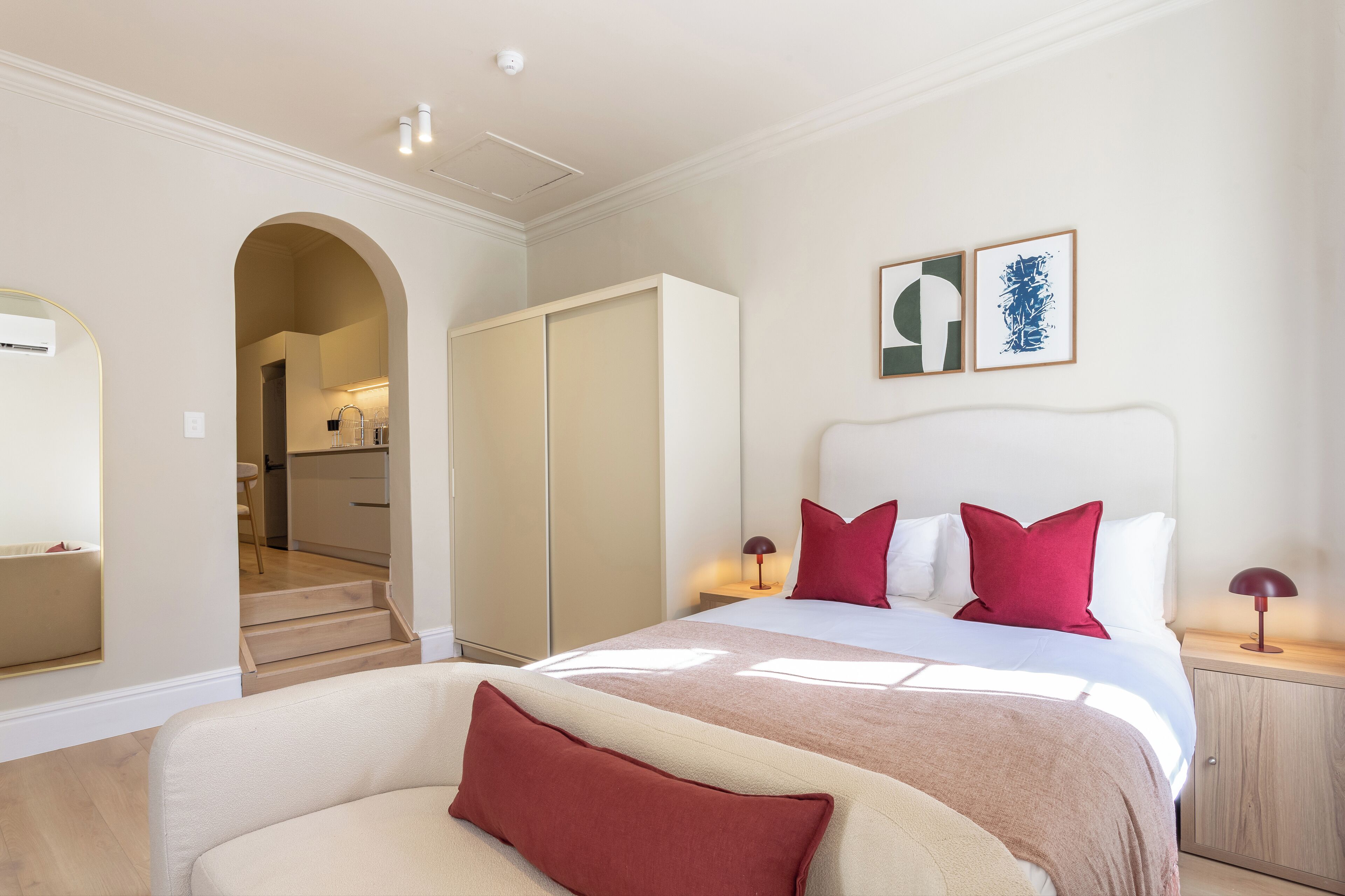 A bedroom with a bed, a wardrobe, a nightstand, and a mirror.