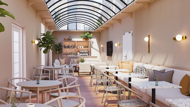 Un interior moderno con una zona de estar central, mesas y sillas, una cocina al fondo y un techo de cristal.