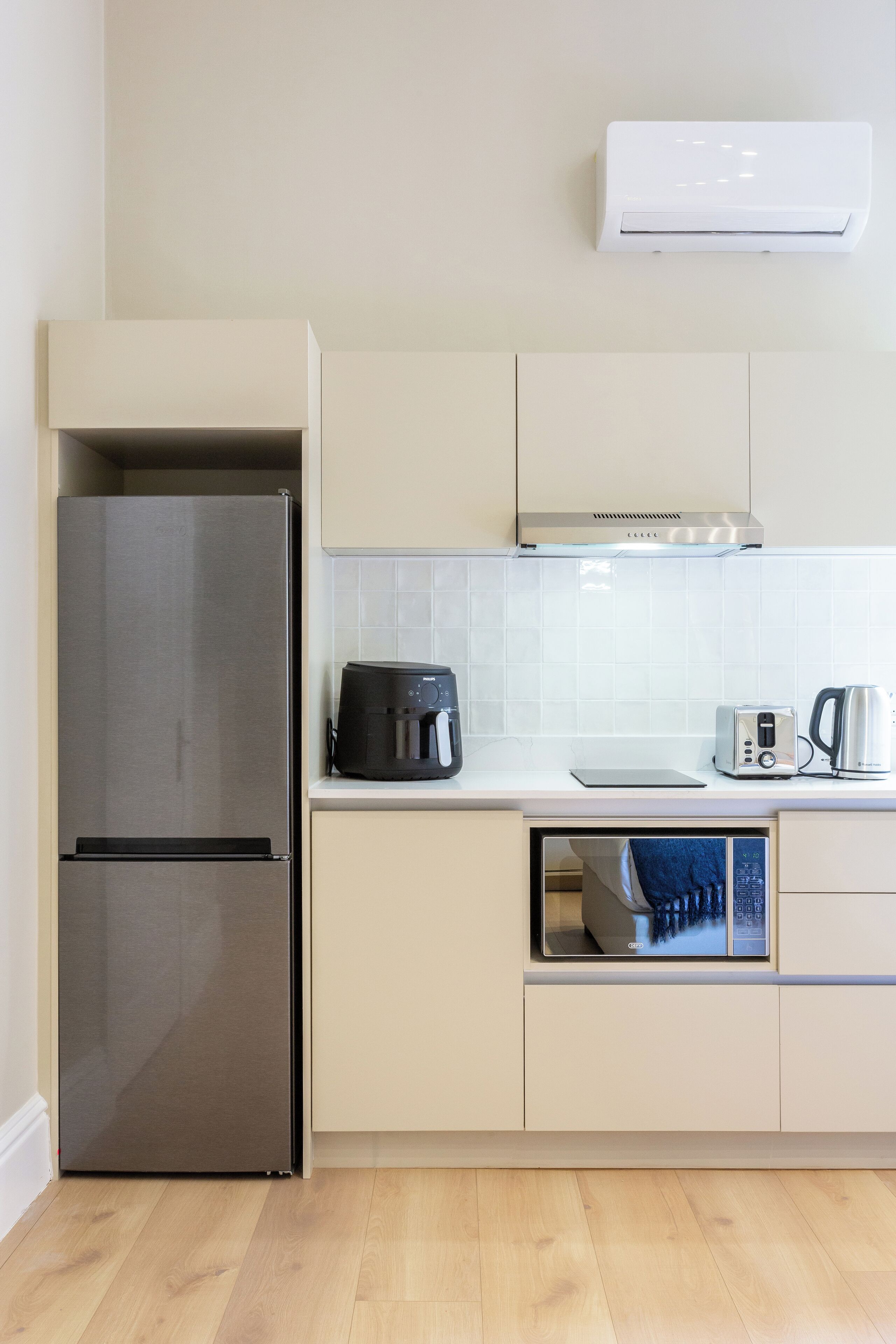 A modern kitchen with a stainless steel refrigerator, a coffee maker, a toaster, and a microwave.